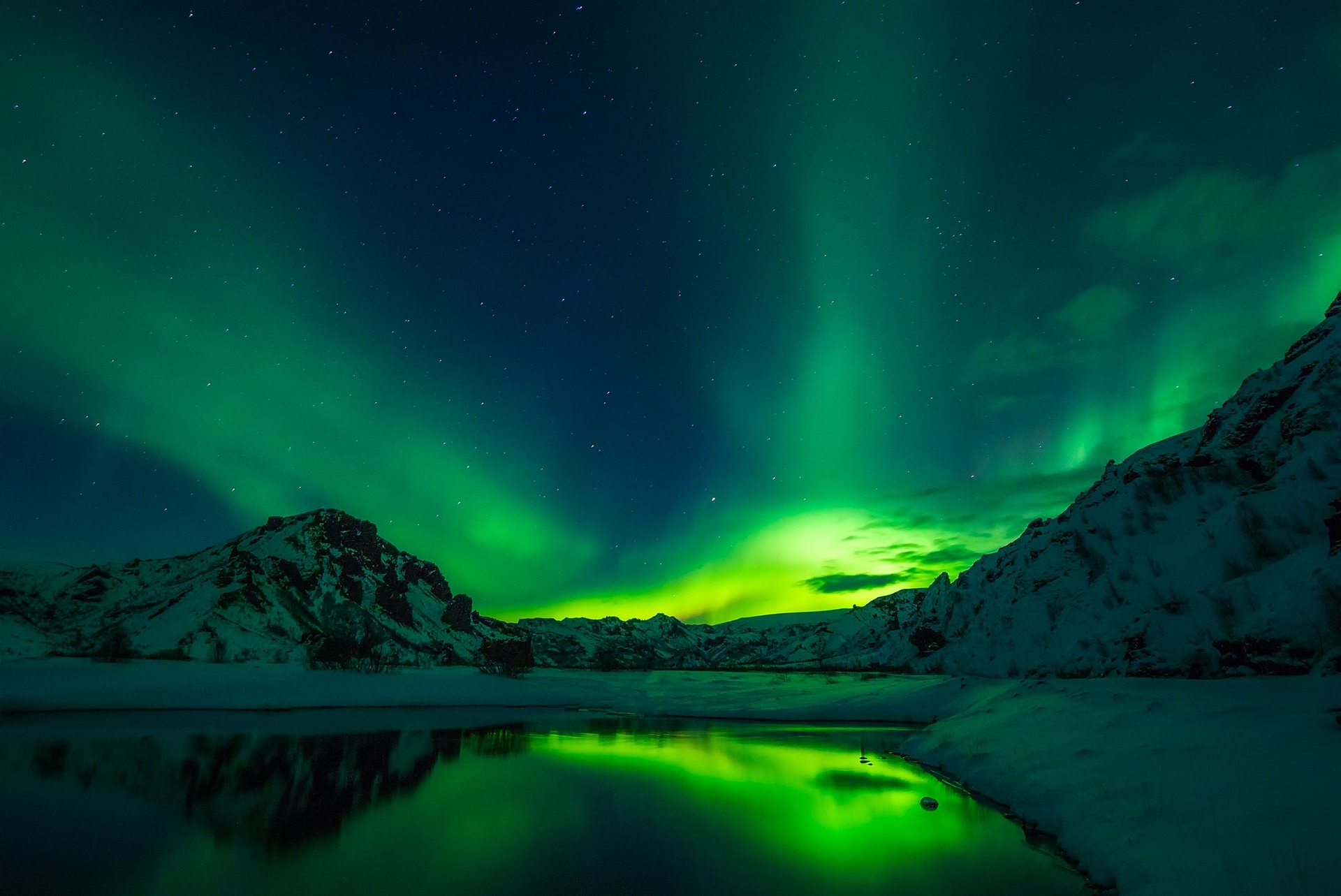 Perfect mirror-like reflection of bright green aurora borealis in calm Arctic fjord with dramatic mountains